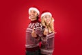 Special Xmas offer. Romantic millennial couple in Santa hats pointing at camera over red background