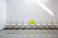 Special yellow chair in the same row with white chairs along the wall in office corridor