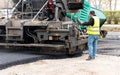 The specialist adjusts the paver before laying the adjacent pavement