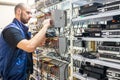 Specialist connects coaxial television wires in the rack of the TV station server room. Man switches audio and video cable on the