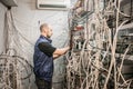 Specialist connects coaxial television wires in the rack of the TV station server room. Man switches audio and video cable on the