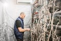 Specialist connects coaxial television wires in the rack of the TV station server room. Man switches  audio and video cable on the Royalty Free Stock Photo