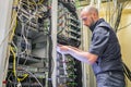 A specialist connects the wires in the server room of the data center. A man works with telecommunications equipment. The