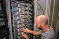 A specialist connects the wires in the server room of the data center. A man works with telecommunications. The technician