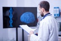 Specialist doctor in a laboratory looking at the scan of a brain holding a clipboard