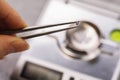 The specialist holds a precious stone in tweezers before weighing it on a jewelry scale