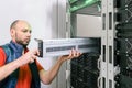 The specialist installs a new battery in the uninterruptible power supply. Replacing the power module in the server room rack.