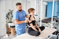 Specialist in a kinesiotherapy clinic glues tape to patients shoulder