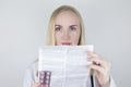 The doctor on a white background reads the instructions for medicines. The specialist looks at the list and composition of the