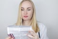 The doctor on a white background reads the instructions for medicines. The specialist looks at the list and composition of the