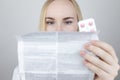 The doctor on a white background reads the instructions for medicines. The specialist looks at the list and composition of the