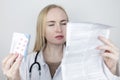 The doctor on a white background reads the instructions for medicines. The specialist looks at the list and composition of the
