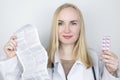 The doctor on a white background reads the instructions for medicines. The specialist looks at the list and composition of the