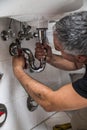 Specialist male plumber repairs faucet in bathroom