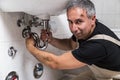 Specialist male plumber repairs faucet in bathroom