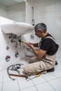 Specialist male plumber repairs faucet in bathroom