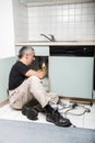 Specialist male plumber repairs faucet in kitchen