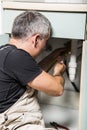 Specialist male plumber repairs faucet in kitchen