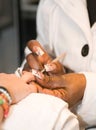 Specialist in nail grooming proceeding to do a manicure on a woman`s hands