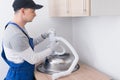 A specialist in protective clothing and gloves, collects and installs a white sewer pipe on a metal sink