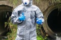 A specialist in protective clothing and a mask holds in one hand a flask with a reagent and shows the thumb up sign with the other Royalty Free Stock Photo