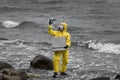 Specialist in protective suit with case and container on rocky shore