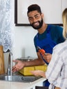 Specialist in uniform fixing leaky faucet, pleased blonde