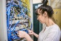 The specialist works in the server room of the data center. The girl is checking the switchboard.  Woman switches the wires in the Royalty Free Stock Photo