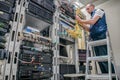 The specialist works in the server room of the data center. Worker lays communication cables. Technological concept. Technician Royalty Free Stock Photo