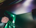 A specialist in wrapping a car with chameleon-colored vinyl film in the process of work.