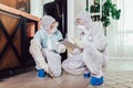 Specialists in protective suits do disinfection or pest control in the apartment