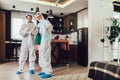 Specialists in protective suits do disinfection or pest control in the apartment