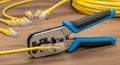 An essential network tool crimping a yellow Cat6 Ethernet cable with an RJ45 connector. Royalty Free Stock Photo