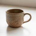 Speckled beige ceramic mug with a rounded shape and single handle. The surface Royalty Free Stock Photo