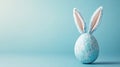 Speckled blue easter egg with bunny ears against soft blue background for a playful happy easter concept Royalty Free Stock Photo