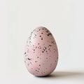 A speckled egg, pastel pink with black speckles