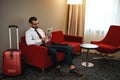 Spectacled business man with newspaper sitting on sofa at hotel hall Royalty Free Stock Photo