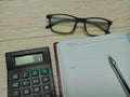 Spectacles, calculator, pen and note book on wood background. Business and finance concept. Royalty Free Stock Photo