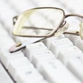 Spectacles lie on keyboard Royalty Free Stock Photo