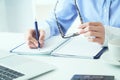 Spectacles placed in businesswoman hand close-up. Young woman writing in notepad. Vision concept Royalty Free Stock Photo