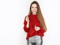 Spectacular blonde woman in red blouse silver leather pants posing with lip glow balm in front of white wall. Graceful girl gorgeo Royalty Free Stock Photo