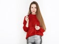 Spectacular blonde woman in red blouse silver leather pants posing with lip glow balm in front of white wall. Graceful girl gorgeo Royalty Free Stock Photo