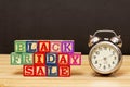 SPECTACULAR CONCEPT OF BLACK FRIDAY AND SALES WITH WOODEN CUBES AND WITH WOODEN SURFACE WITH OLD ALARM CLOCK Royalty Free Stock Photo