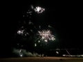 Spectacular fireworks display over a dark beach at night. Bright bursts of light illuminate the sky, creating a vibrant and