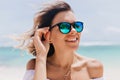 Spectacular girl in trendy sparkle sunglasses enjoying good day at ocean resort. Outdoor portrait of sensual tanned