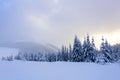 Spectacular panorama is opened on mountains, trees covered with white snow, lawn and blue sky with clouds. Royalty Free Stock Photo