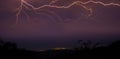 Spectacular shot of lighting bolts over a tranquil city in the distance at night