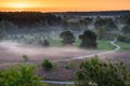 Spectacular sunrise with rays of sun over the blooming purple heather with thin layers of fog.