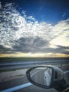 a spectacular sunrise seen from the window of a moving car, in the foreground the driving rearview mirror with the reflection of Royalty Free Stock Photo