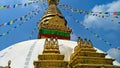 Spectacular view of the golden stupa of the Boudhanath Buddhist temple in Patan adorned with colored prayer flags and a blue sky